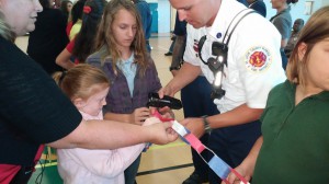 Desire Konicek and Kaitlyn Bright assist a St. Lucie County Firefighter in stapling paper chains together, with a little help from School Counselor Sheri Reichard. 