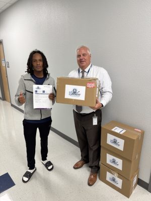 Mr. Smith and a student pose for a picture with delivered packages.