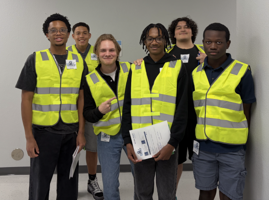 Logistics students in reflective vests pose for a picture.